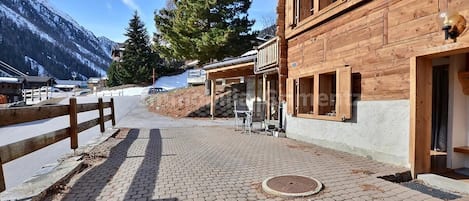 Un bâtiment en bois doté d’un espace extérieur abrité avec des sièges et d’un chemin piétonnier pavé.