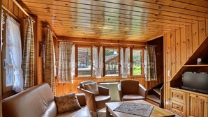 A wooden cabin interior with a sofa, chairs, a coffee table, a TV, and large windows with curtains. - Comfortable flat on 2 levels for 3 to 4 people, living room, kitchen area, 1 double bedroom (140), 1 (Grimentz)