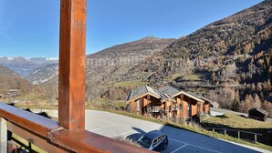 Eine Holzhütte mit geneigtem Dach, gelegen an einem Hang mit Blick über ein Tal und Berge im Hintergrund.