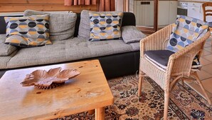 Ein gemütlicher Wohnbereich mit einer Couch, Sesseln, einem Esstisch und einem Couchtisch.