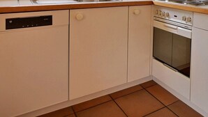 Eine Küche mit weißen Schränken, einem Geschirrspüler, einem Backofen und einer Mikrowelle.