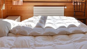 Ein Schlafzimmer mit einem hölzernen Kopfende, einem Bett mit weißer Bettwäsche und einem Sessel.