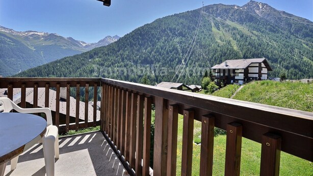 Ein Balkon mit Blick auf einen Berg und eine Chalet.