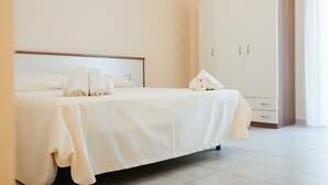 A neatly made bed with white linens and towels, a large wardrobe, and a clean, minimalist room design. - Hotel Parnaso (Trebisacce)