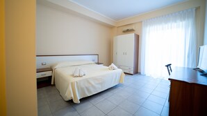 A hotel room with a bed, a desk, a wardrobe, and a window with curtains. - Hotel Parnaso (Trebisacce)
