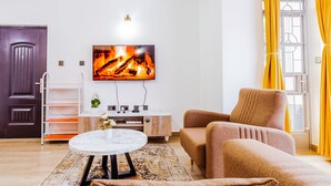 Moderni olohuone, jossa on litteänäyttöinen televisio, sohva, sohvapöytä ja koristeellinen matto.