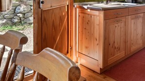 A wooden kitchen with a sink, stove, and cabinets.