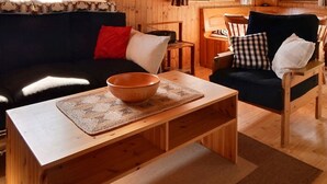 A cozy wooden interior with a sofa, armchairs, and a table with a bowl.