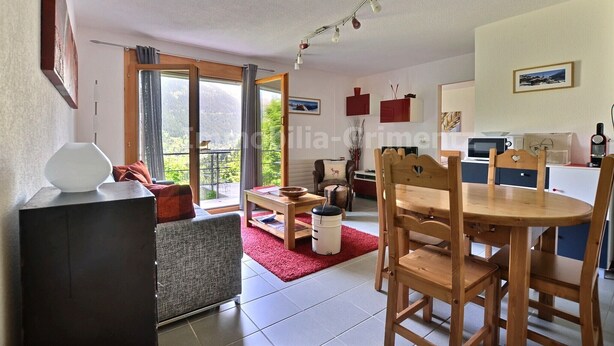 A spacious living area with a dining table, chairs, a sofa, and a kitchen in the background. - Comfortable flat for 2 to 4 people, living room with 1 double divan bed, kitchen area with dishwashe (Grimentz)