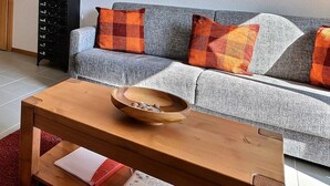 A kitchen with wooden chairs, a dining table, and a sofa with patterned cushions. - Comfortable flat for 2 to 4 people, living room with 1 double divan bed, kitchen area with dishwashe (Grimentz)
