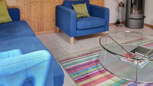 A living room with a blue sofa, a glass coffee table, and a striped rug.