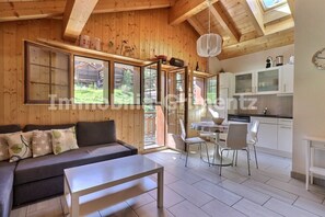 Un acogedor interior de cabaña con sofá, mesa de comedor y zona de cocina.