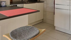 A kitchen with white cabinets, a black countertop, and a red mat.
