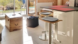 A modern kitchen with a wooden island, bar stools, a built-in oven, and a view of the outdoors.