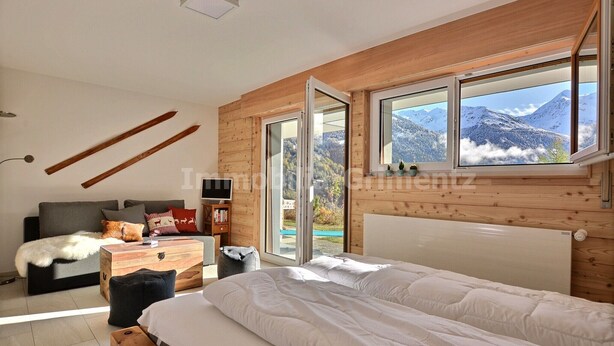 A bedroom with a large bed, a wooden headboard, and a view of mountains through a window.