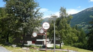 A signpost with multiple circular signs, one of which reads "LES RUCHES". - Middle class flat for 5 people, living room with fireplace, kitchen area with dishwasher, 1 bedroom (Grimentz)