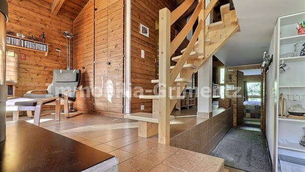 Una habitación amplia con una escalera de madera, un sofá y una estantería.