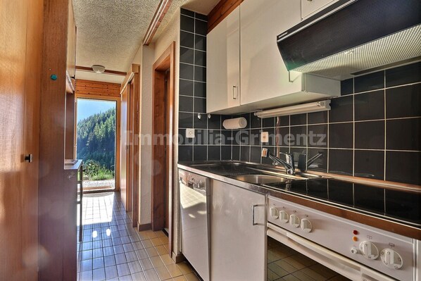 A kitchen with a stove, sink, and cabinets.