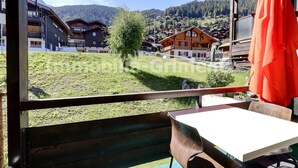 A balcony with a table and chairs, overlooking a village with traditional houses and a mountain in the background. - Middle class flat for 4 people, small living room with fireplace, kitchen area with dishwasher, 1 sm (Grimentz)