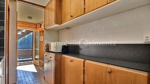 A kitchen with wooden cabinets, a black countertop, and a view of a balcony. - Middle class flat for 4 people, small living room with fireplace, kitchen area with dishwasher, 1 sm (Grimentz)