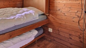 Una litera con colchón y almohadas, paredes de madera y un enchufe.