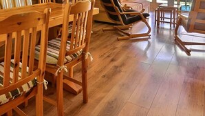 Una mesa de comedor de madera con sillas, un sofá y un sillón mecedora en una habitación con piso de madera.