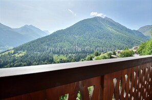 A mountainous landscape with a wooden balcony railing.