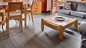 A living room with a grey sofa, wooden chairs, a coffee table, and a dining area with a table and chairs. - Comfortable flat on 2 levels for 4 to 6 people, living room, kitchen area with dishwasher, 1 double (Grimentz)