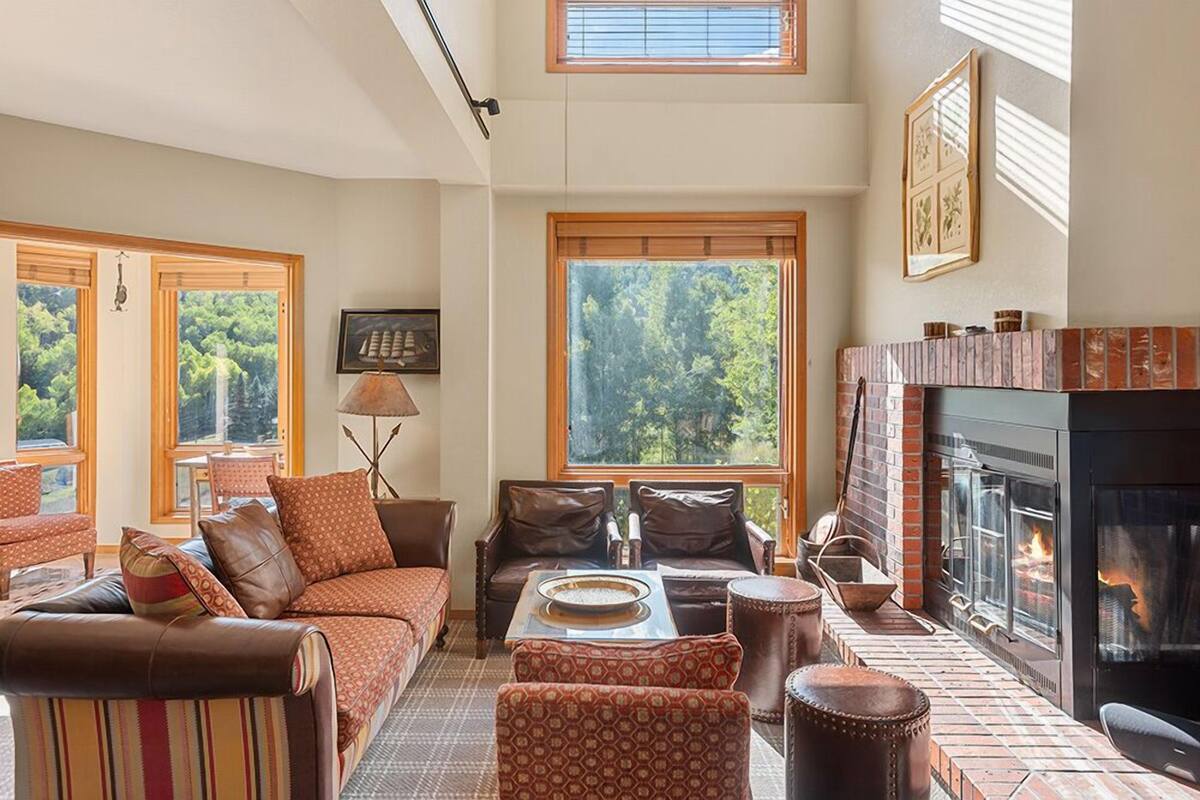 A cozy living room with a fireplace, large windows, and comfortable seating.