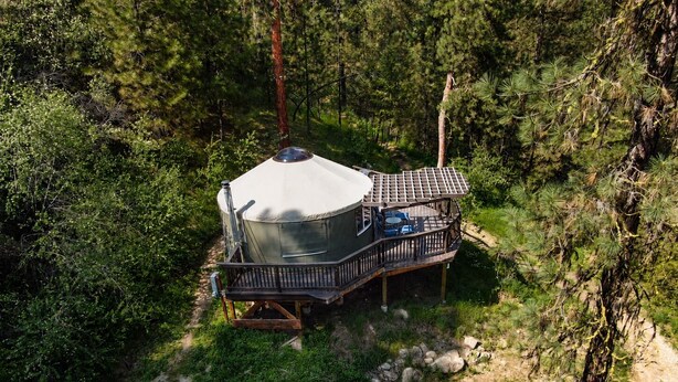 Une cabane dotée d’une terrasse couverte, entourée d’une forêt dense.