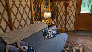 Une pièce comprenant un lit, une table de chevet avec une lampe, un tapis à motifs et un mur décoré d’un treillis en bois.