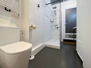 Een moderne badkamer met een toilet, een douchecabine en een toiletrolhouder.