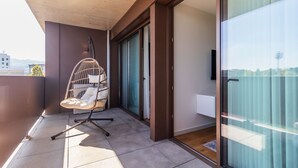 A balcony with a hanging chair, sliding glass doors, and a view of the city. - Contemporary Oasis w/ Balcony by LovelyStay (Vila Nova de Gaia)