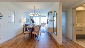 A modern dining area with a wooden table and chairs, a chandelier, and a view into the living room. - Contemporary Oasis w/ Balcony by LovelyStay (Vila Nova de Gaia)