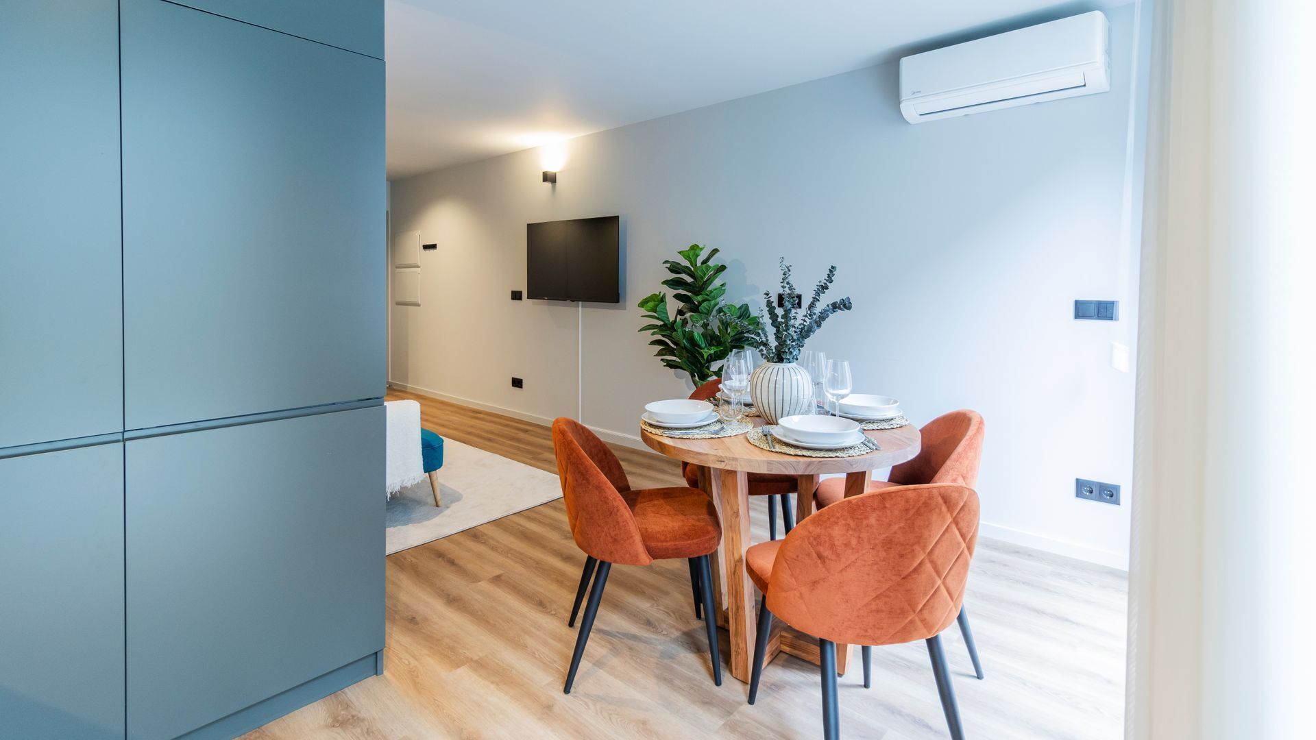 Un espace repas moderne avec une table ronde, quatre chaises orange et une plante en pot.