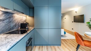 A modern kitchen with a built-in stove, a coffee maker, and a TV mounted on the wall. - RUAH C - Cozy Studio by LovelyStay (Vila Nova de Gaia)