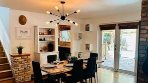 Un espace repas avec une table en bois, des chaises noires et un lustre moderne.