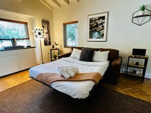 Un dormitorio moderno con una cama grande, una mesita de noche, un escritorio y una ventana con persianas.