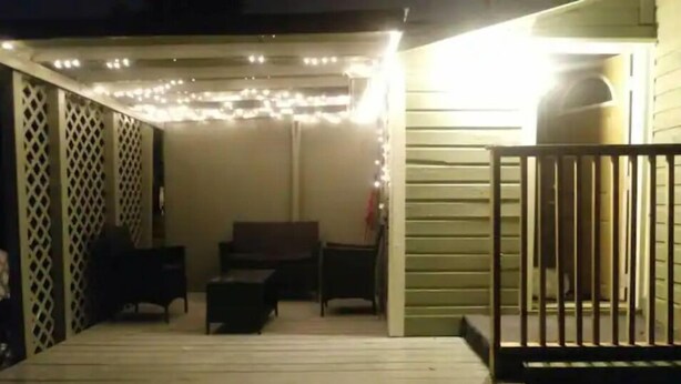 Un espace extérieur abrité, doté d’une terrasse en bois, d’un banc et d’une table.