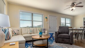 A living room with a sofa, armchair, coffee table, and a dining area with a table and chairs. - Gulf Side-Walk to the beach, great views, pet-friendly - Boa Vista (Dauphin Island)