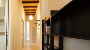Un couloir doté d’un plancher en bois, d’une bibliothèque noire et d’un luminaire suspendu.