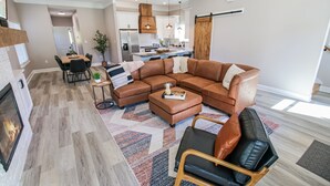 Ein modernes Wohnzimmer mit einer Eckcouch, einem Kamin und einem Essbereich.