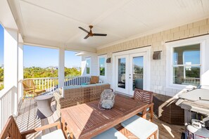A covered outdoor deck with wooden furniture, a ceiling fan, and a view of the ocean. - Stunning S Beach Retreat Shoals & BHI Club available 4 night min in July (Bald Head Island)