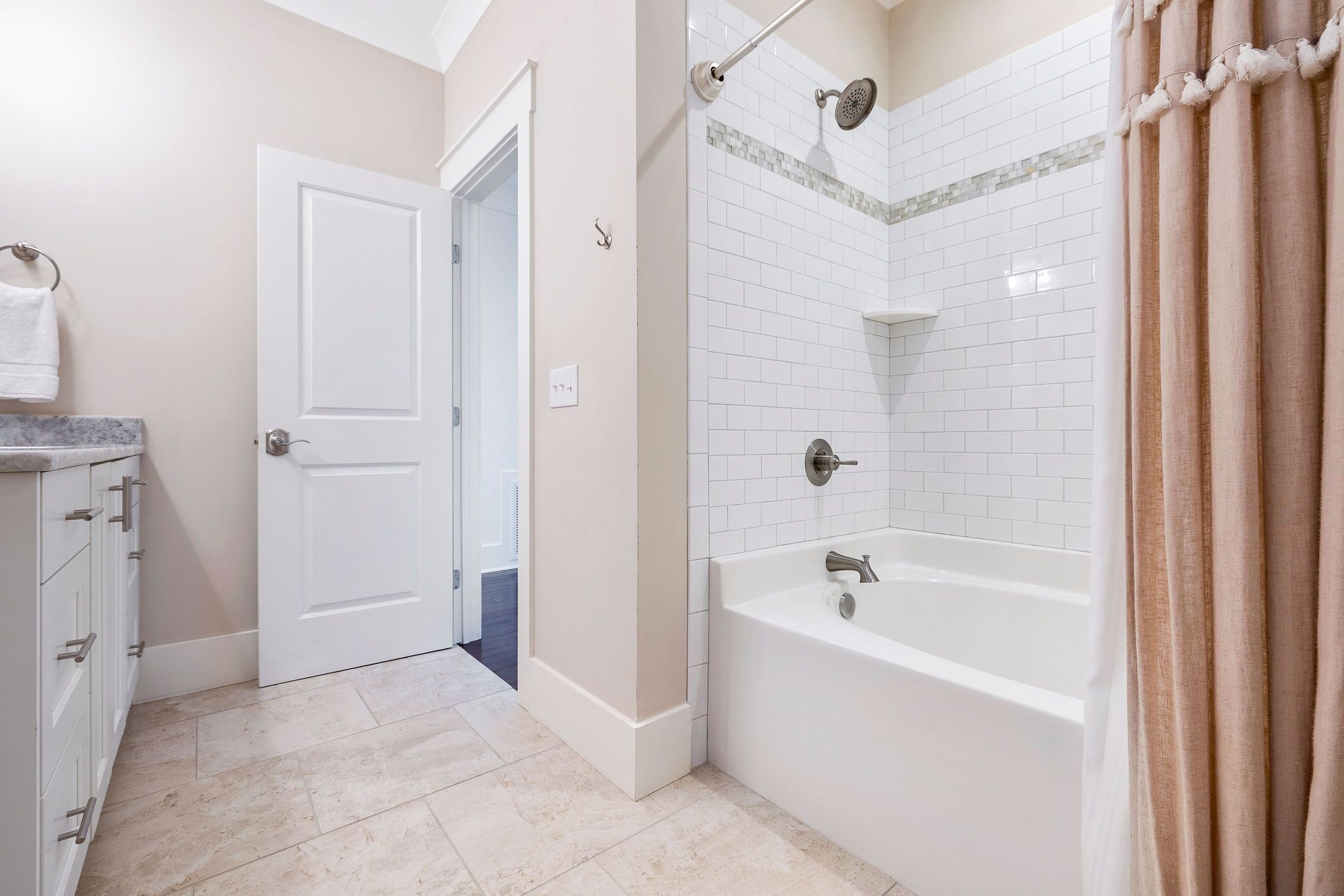 A bathroom with a bathtub, shower, and a door leading to another room.