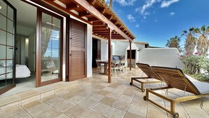 Une terrasse dotée d’une pergola en bois, d’un barbecue et d’un fauteuil de relaxation.