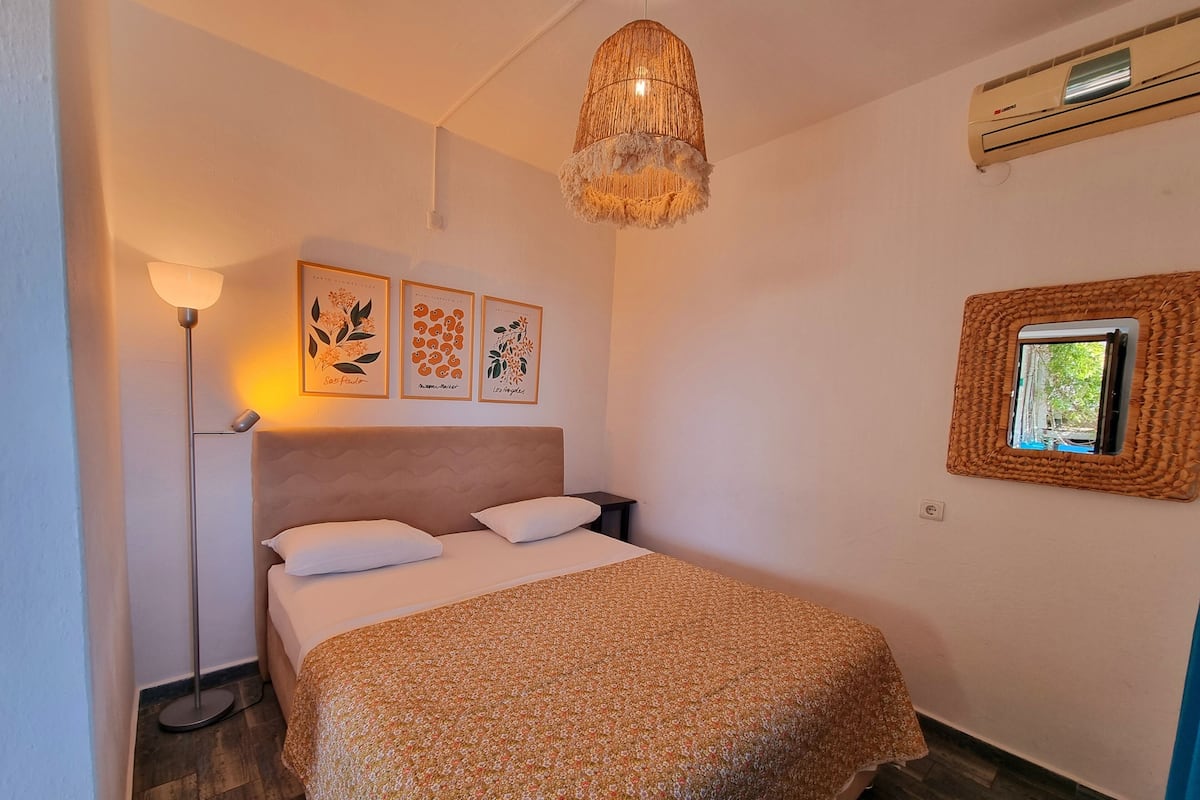 Un dormitorio con cama, lámpara de pie, decoración en la pared y una ventana con marco de mimbre.