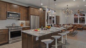 Une cuisine moderne avec des meubles en bois, des appareils en acier inoxydable et un grand îlot central doté de tabourets de bar.