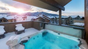 Un bain à remous sur un balcon avec vue sur une montagne enneigée.
