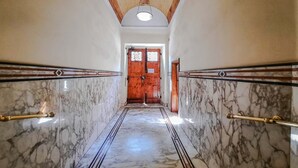 A marble-floored hallway with wooden doors and a ceiling light. - Colosseum Cosy Apartment Close To Metro (Rome)