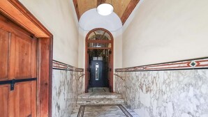 A marble-floored hallway with wooden doors and a ceiling light. - Colosseum Cosy Apartment Close To Metro (Rome)